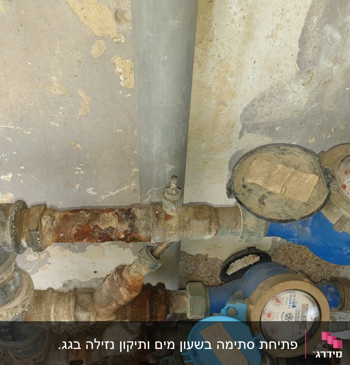 מד מים כחול עם צינורות חלודים וקירות מתקלפים